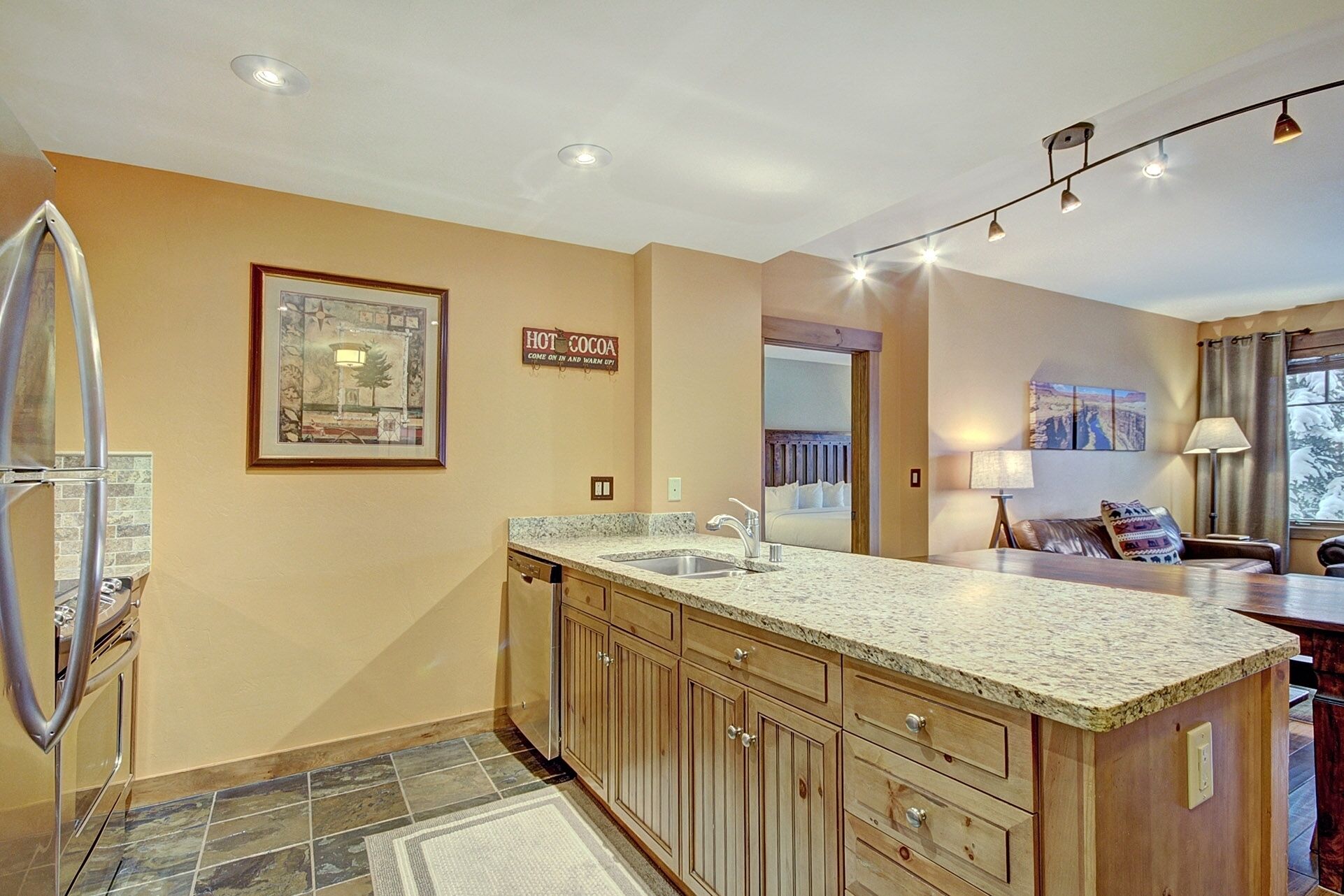 A kitchen with a granite countertop, wooden cabinets, and a built-in dishwasher.