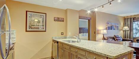 A kitchen with a granite countertop, wooden cabinets, and a built-in dishwasher.