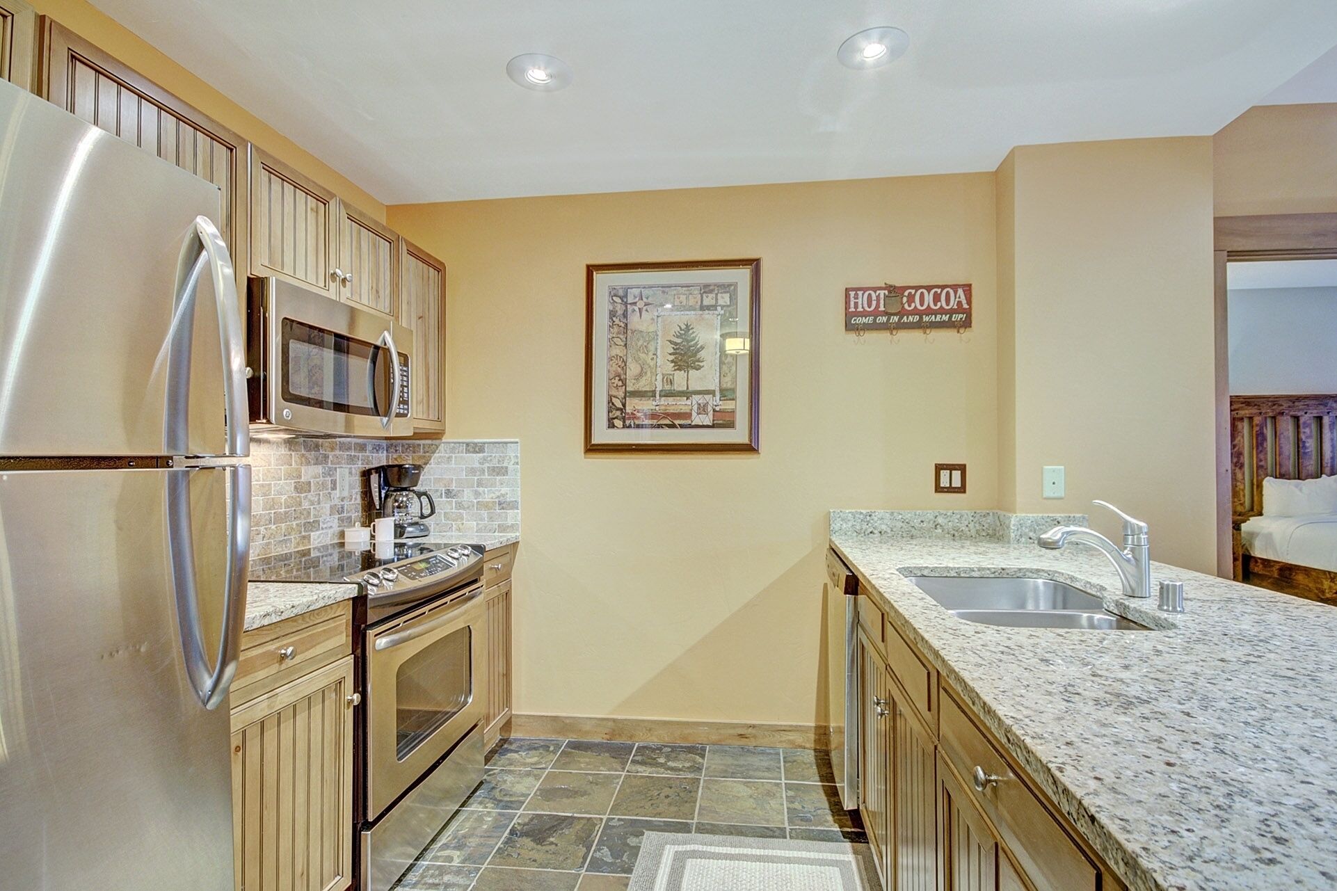 Una cocina con electrodomésticos de acero inoxidable, encimera de granito y salpicadero de azulejos.