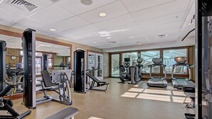 Un gimnasio con diversos equipos de ejercicio, amplias ventanas y un diseño moderno y limpio.