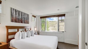 Un dormitorio con una cama grande, un cuadro y una ventana con vistas a un campo.