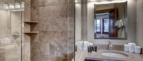 A modern bathroom with a glass-enclosed shower, a vanity with a sink, and a large mirror.