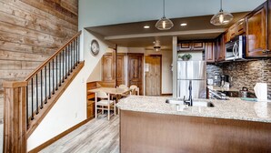 Una cocina moderna con escaleras de madera, encimeras de granito y una isla central.