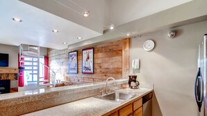 A modern kitchen with granite countertops, wooden cabinets, a stainless steel sink, and a built-in oven. - Plaza 1407 (Keystone)