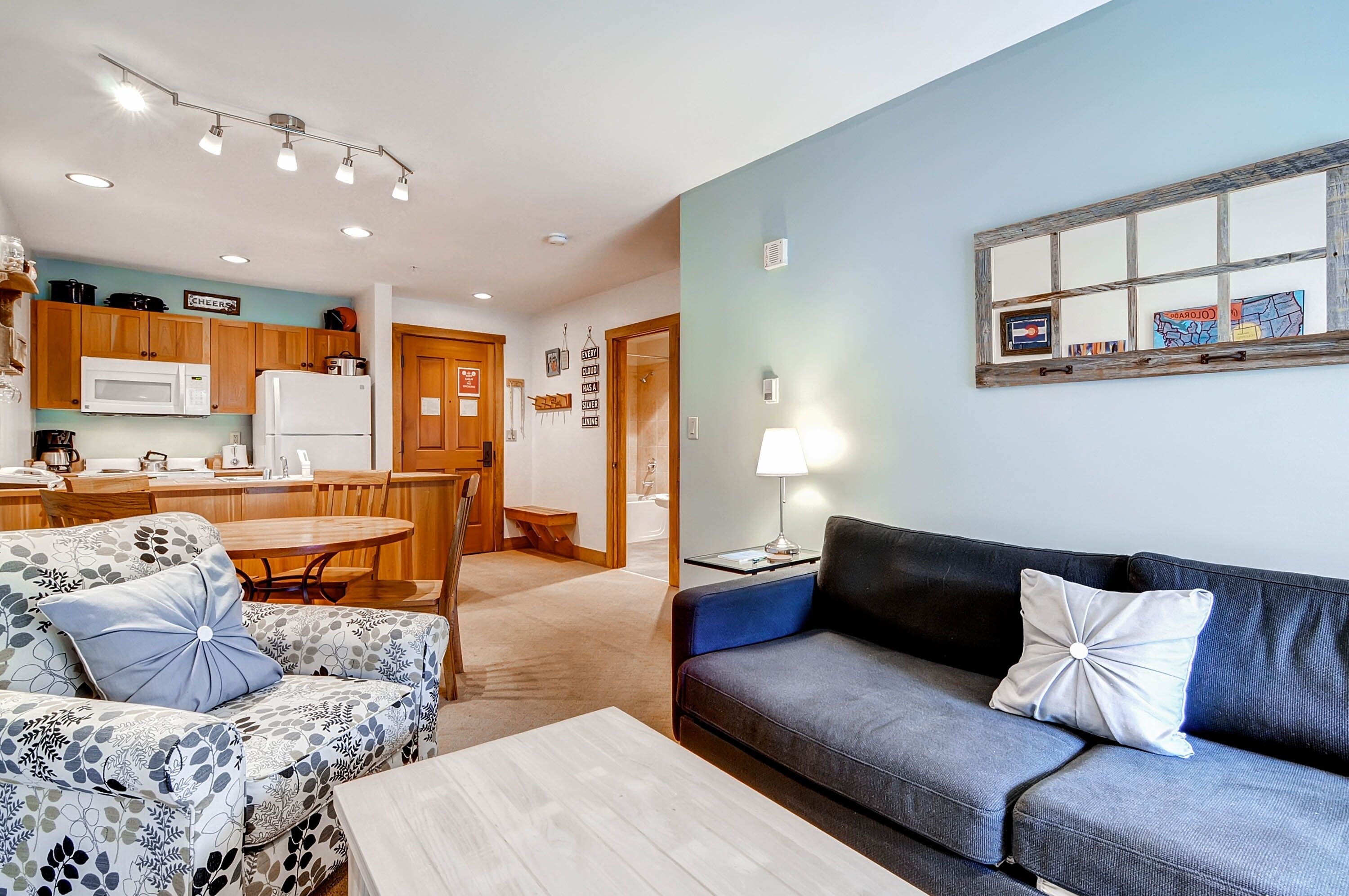 A modern living room with a sofa, a coffee table, and a dining area with a table and chairs.