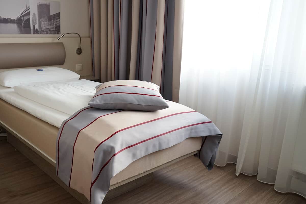 A neatly made bed with a striped bedspread, a pillow, and a headboard.