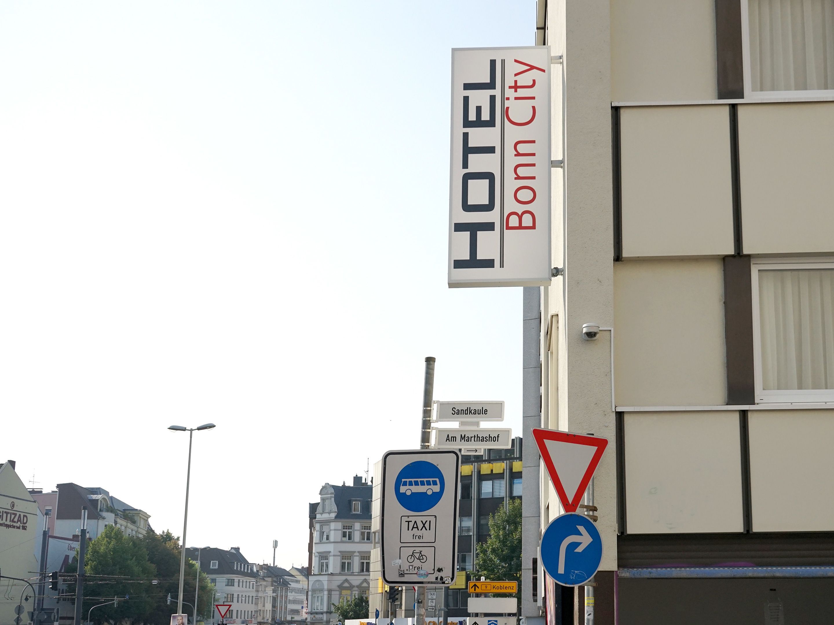 Segnale di un hotel con su scritto "HOTEL Bonn City" e indicazioni direzionali per "Sandkaul" e "Am Marthashof".