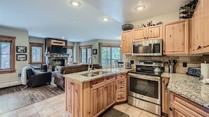 A spacious kitchen with wooden cabinets, granite countertops, stainless steel appliances, and a large island.