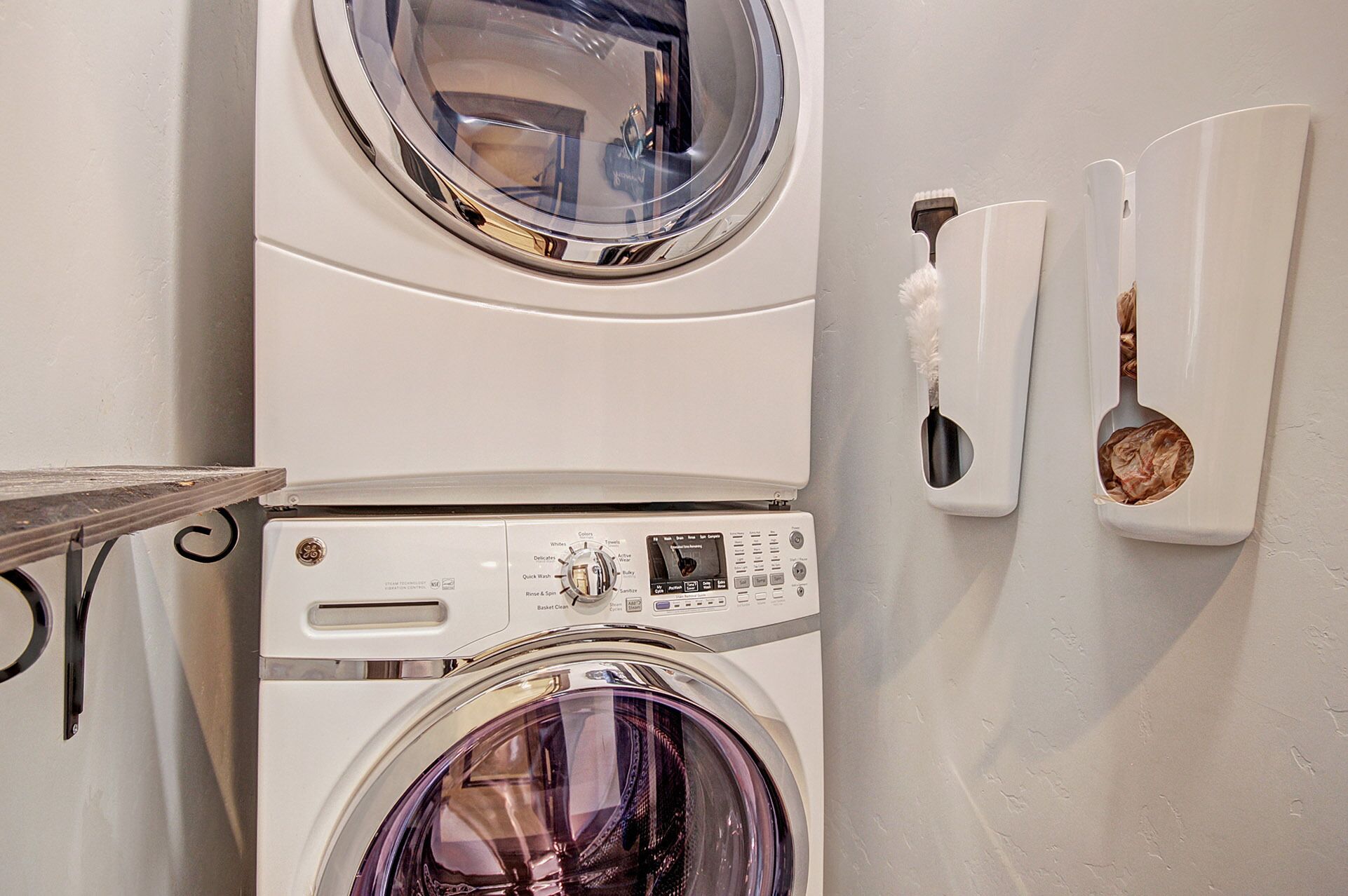 A laundry area with two stacked washing machines and a wall-mounted drying rack.