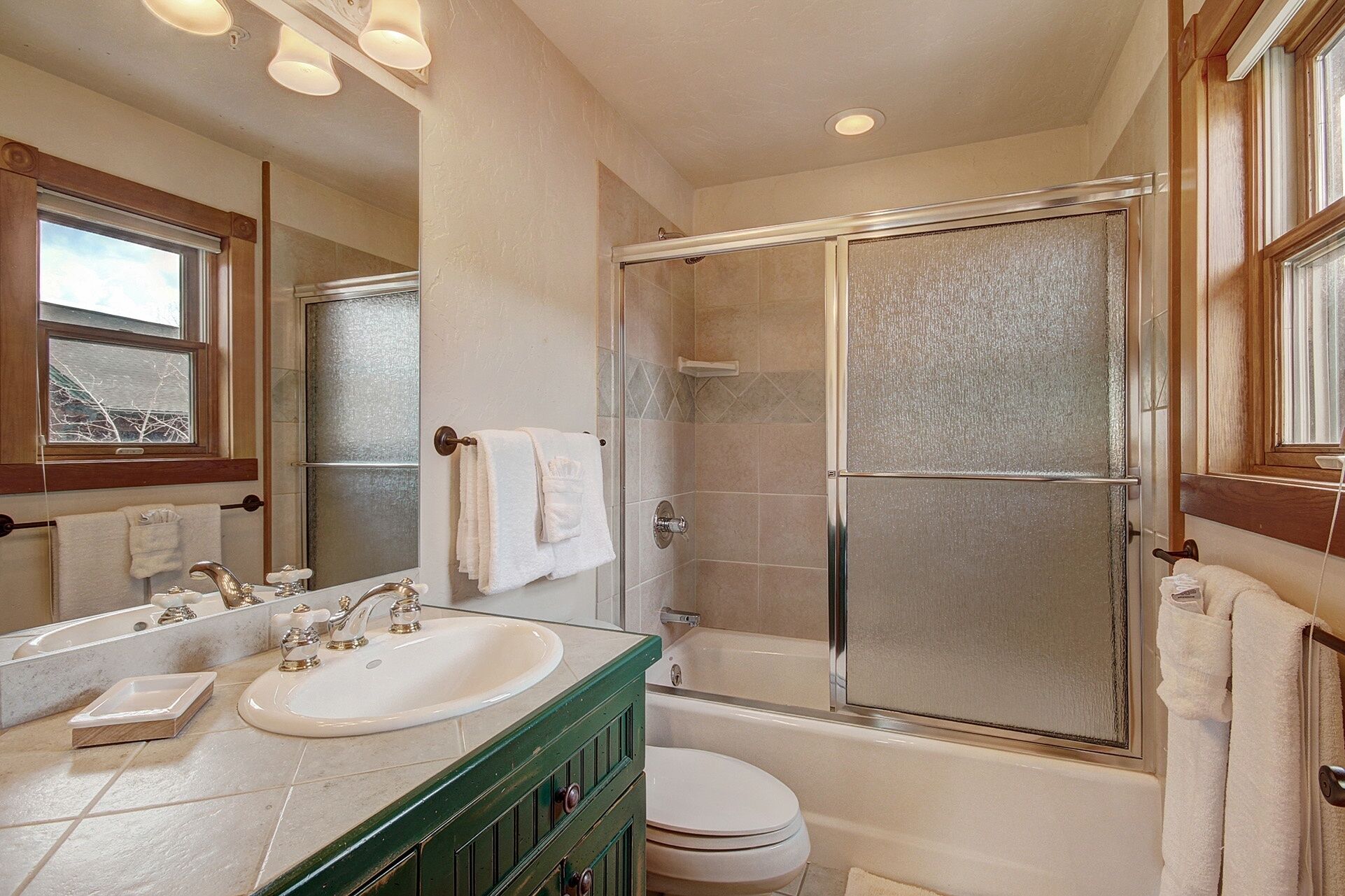 A bathroom with a glass-enclosed shower, a white sink, and a toilet.