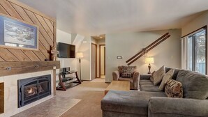 A living room with a fireplace, a sofa, a coffee table, and a television. - 1125 Flying Dutchman 1 Bedroom Condo by RedAwning (Keystone)
