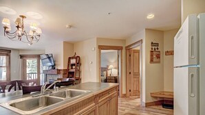 A kitchen with wooden cabinets, a double sink, a chandelier, and a refrigerator. - 8824 The Springs 2 Bedroom Condo by RedAwning (Keystone)