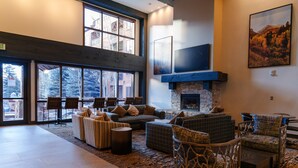 A spacious lobby with a fireplace, comfortable seating, large windows, and a modern design.
