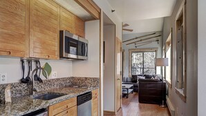 Een moderne keuken met houten kastjes, een ingebouwde magnetron, granieten aanrecht en een vaatwasser.