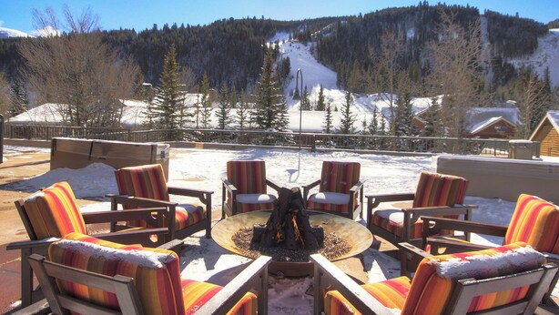A patio with outdoor seating and a fire pit, overlooking a snowy mountain landscape. - 2759 Slopeside 1 Bedroom Condo by RedAwning (Keystone)