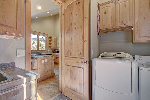 A kitchen with wooden cabinets, a stainless steel countertop, a built-in oven, and a washing machine.