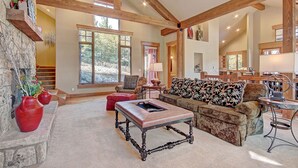 A spacious living area with a stone fireplace, large windows, and a cozy seating arrangement. - 170 Elk Circle by RedAwning (Keystone)