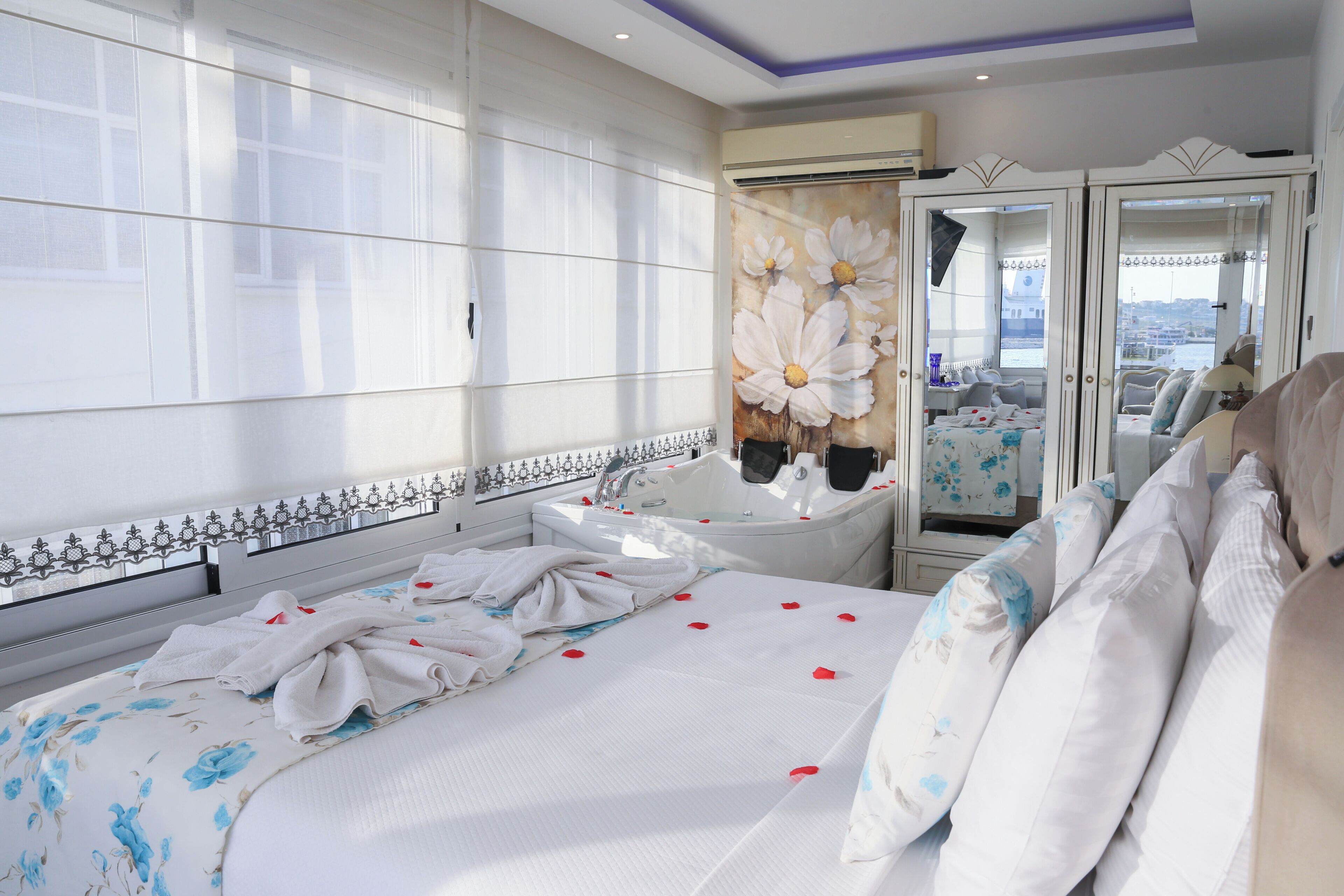 A hotel room with a large bed, a bathroom with a bathtub, and a view of the city.