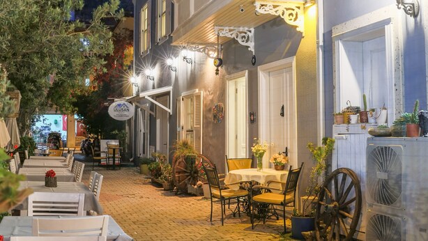 A traditional European-style building with a courtyard, outdoor seating, and a vintage fan. - Dantela Butik Hotel (Cesme)