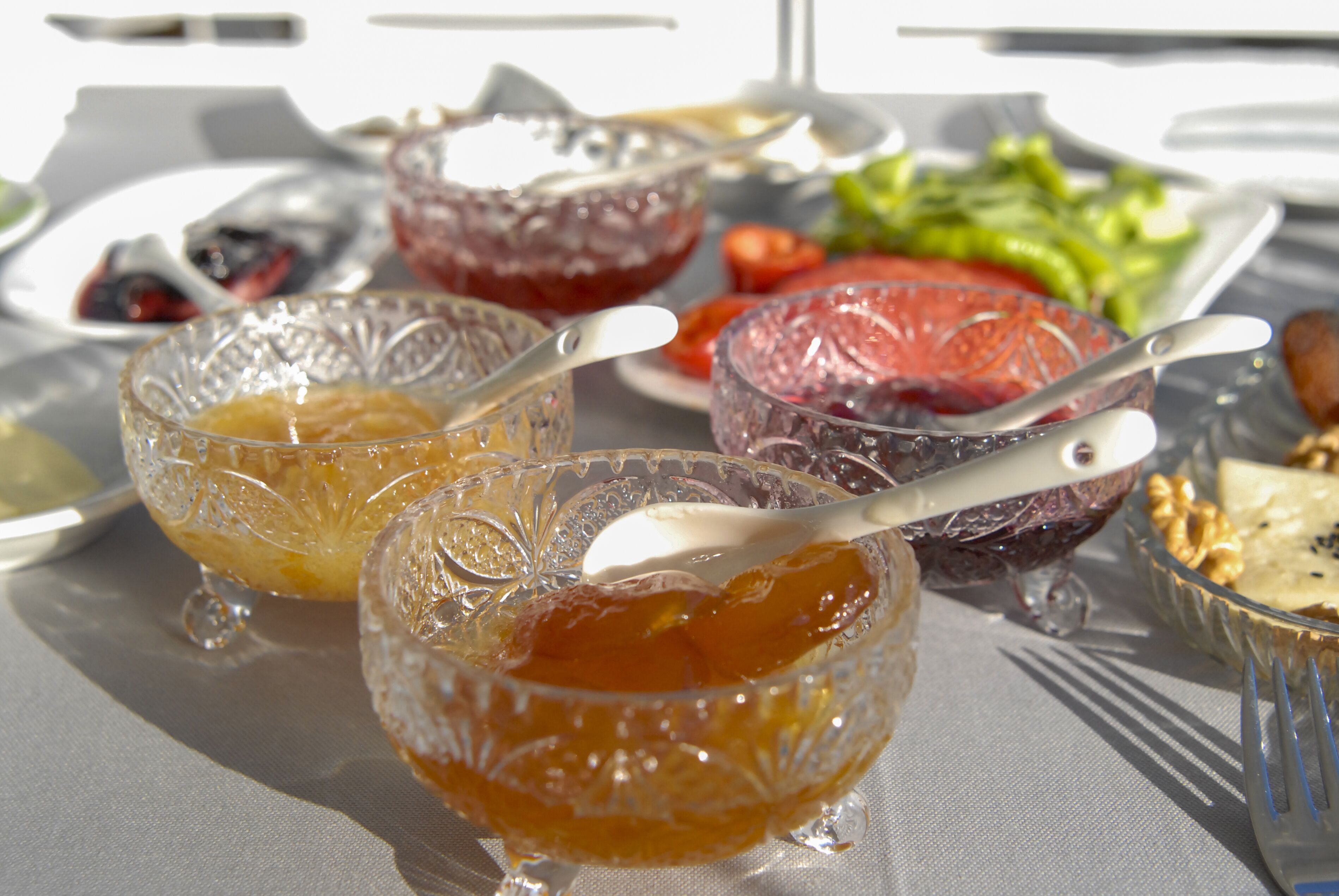A table with various food items including bowls of fruit preserves and a salad.