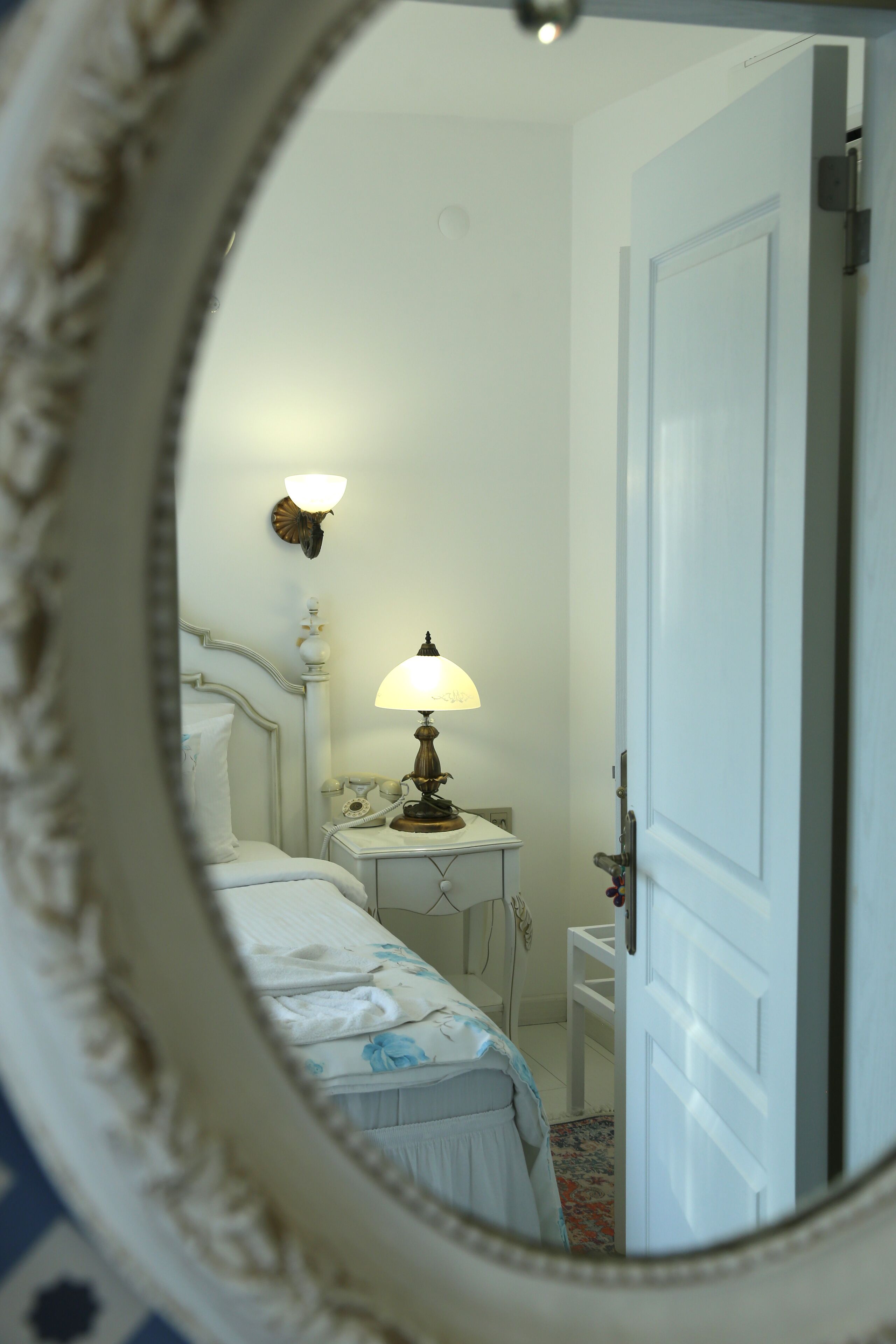 A bedroom with a bed, bedside table, lamp, and a door.