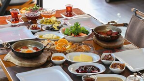 A dining table set with various dishes, including bread, fruits, and a bowl of soup. - Dantela Butik Hotel (Cesme)
