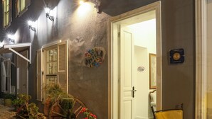 A hotel entrance with a rustic exterior, a wooden cart with potted plants, and a sign indicating a 9.6 rating. - Dantela Butik Hotel (Cesme)