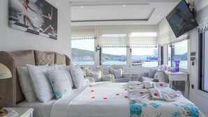 A hotel room with a bed, a TV, a desk, and a view of the sea. - Dantela Butik Hotel (Cesme)