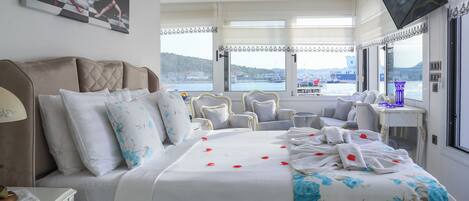 Habitación de hotel con cama, televisor, escritorio y vista al mar.