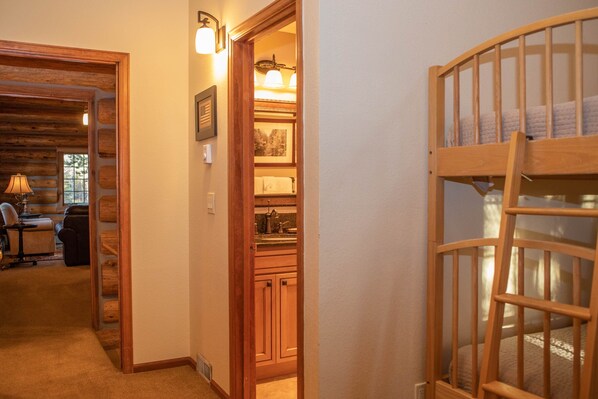 A hallway leading to a kitchen with wooden cabinets and a bunk bed with a window.