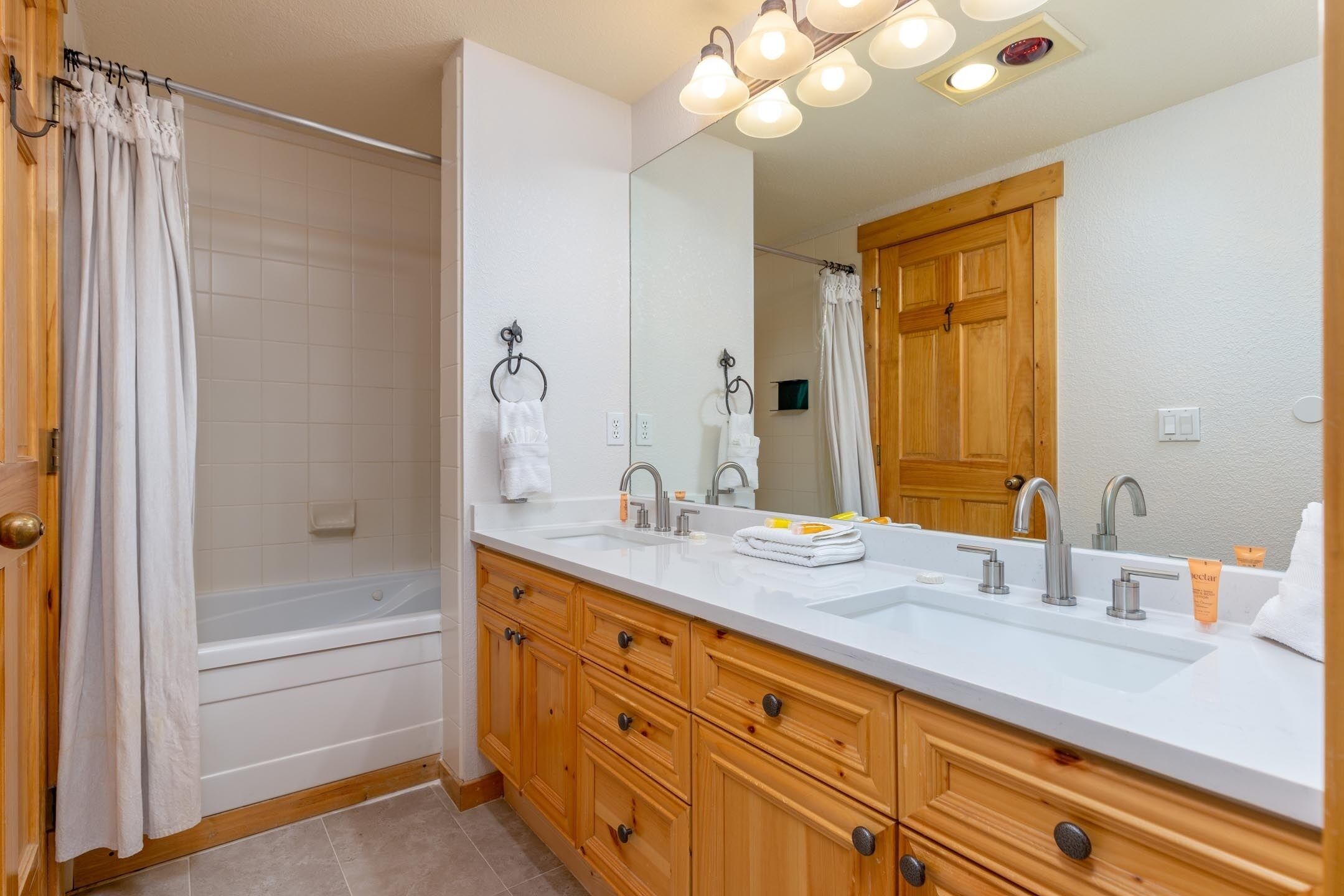 Une salle de bain moderne avec une baignoire, un grand miroir et des meubles en bois.