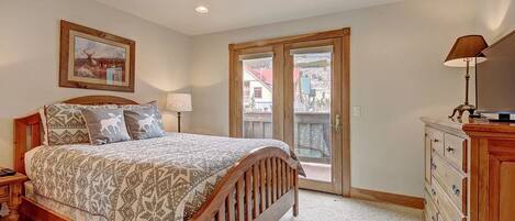 Un dormitorio con una cama de madera, un aparador, una mesita de noche, una lámpara y un cuadro en la pared.