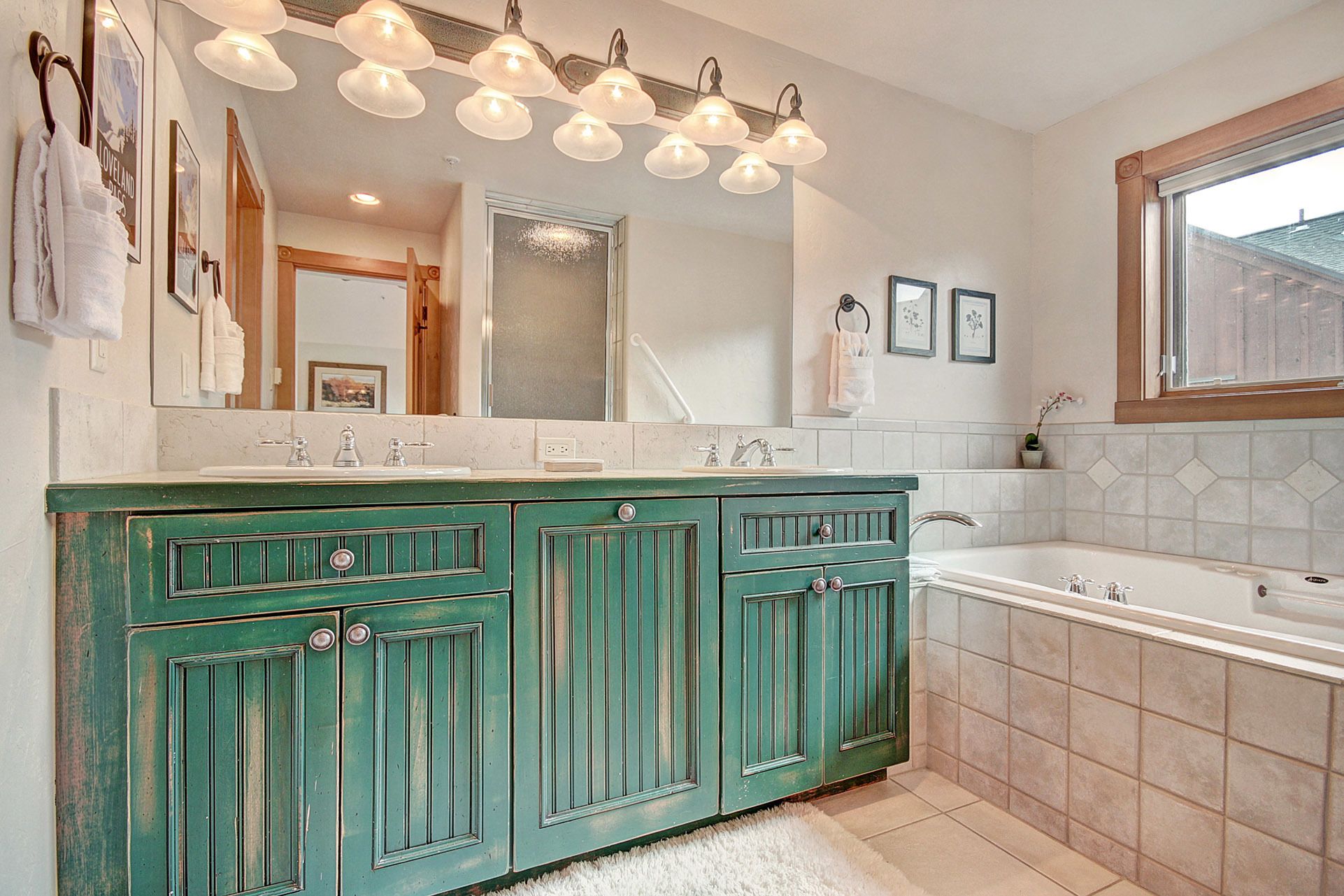 Un baño con tocador verde, un espejo grande y una bañera.