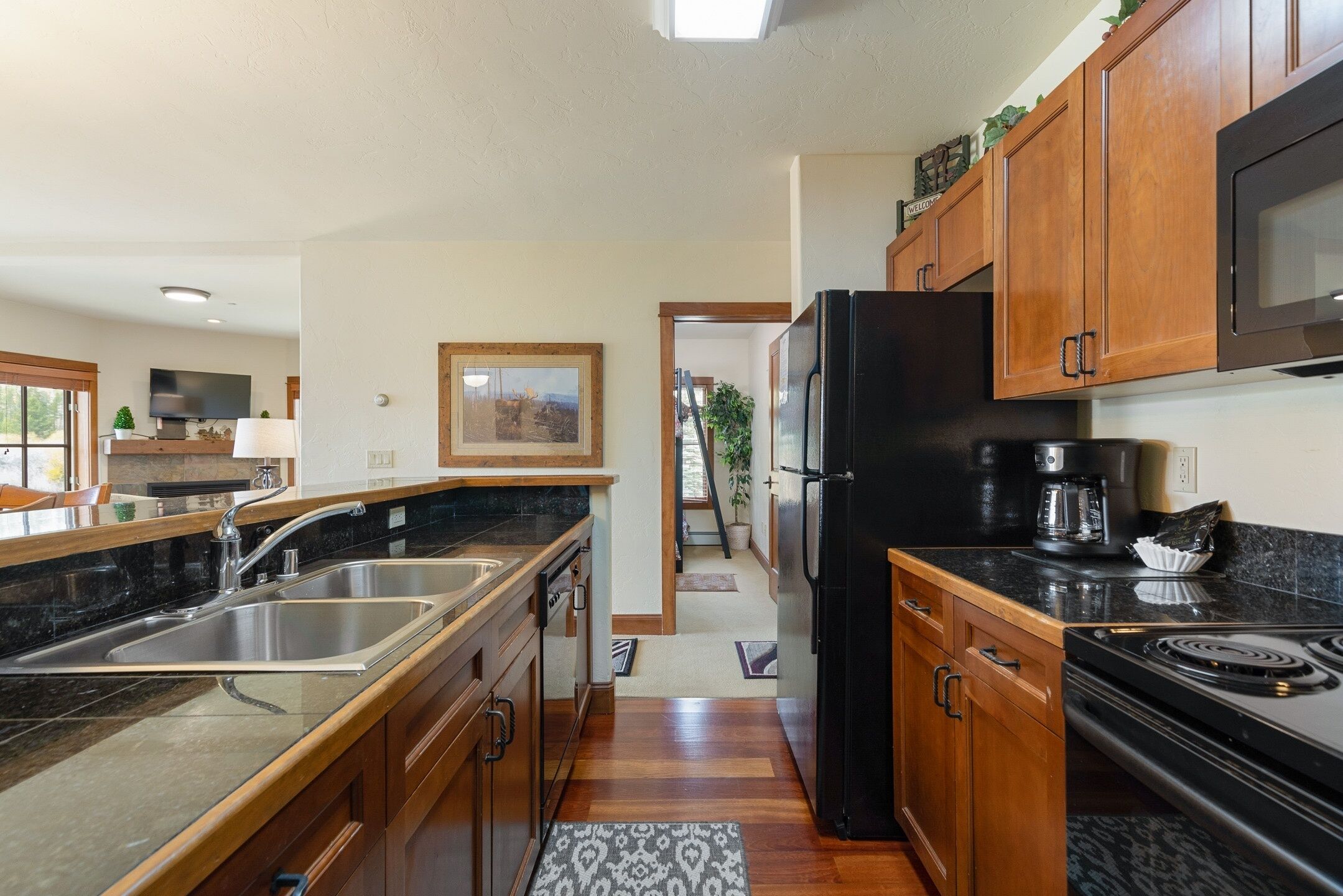 A modern kitchen with wooden cabinets, a black refrigerator, a stove, and a sink.