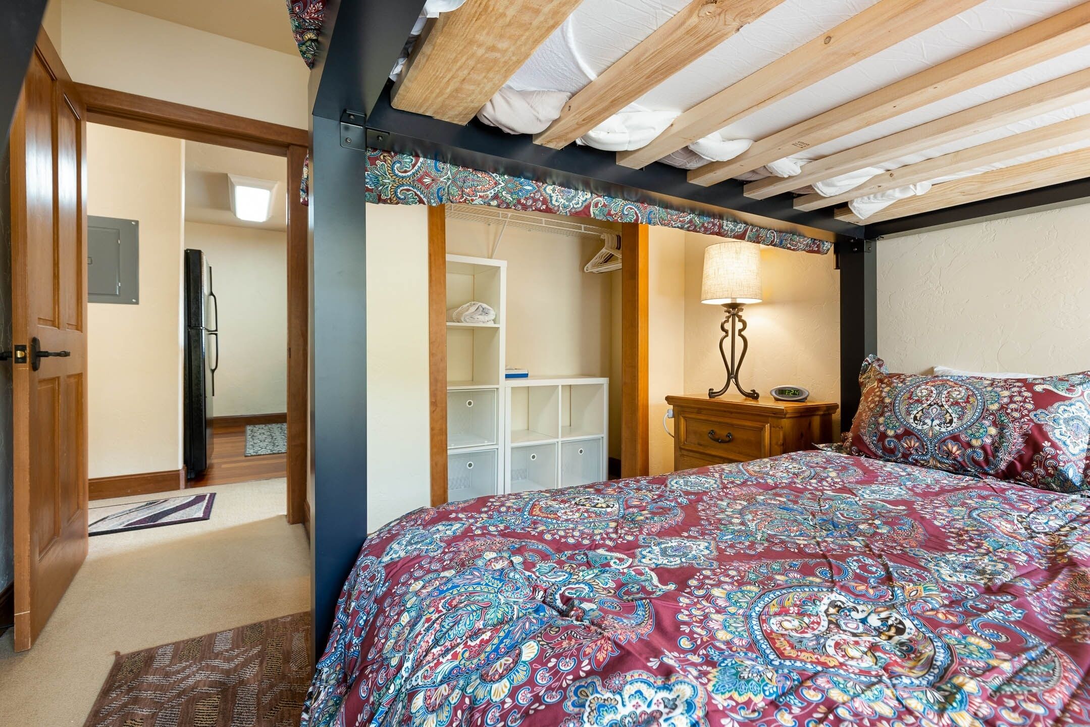 A bedroom with a large bed, a wardrobe, a bedside table, and a lamp.