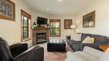 A living room with a fireplace, a sofa, a coffee table, and a television.