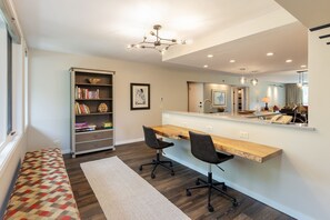 A modern home office with a desk, two chairs, a bookshelf, and a large mirror. - 2112 The Pines by RedAwning (Keystone)