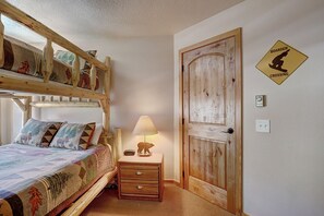 Cozy bedroom with a wooden bunk bed, bedside table, and decorative elephant figurine.