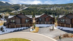 A row of modern log cabins with large windows and balconies, set in a snowy landscape with a forested mountain in the background. - 47 River Run Townhomes 3 Bedroom Townhouse by RedAwning (Keystone)