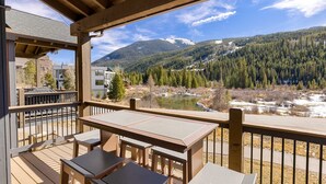 A wooden deck with outdoor seating overlooking a lake and forested mountains. - 47 River Run Townhomes 3 Bedroom Townhouse by RedAwning (Keystone)