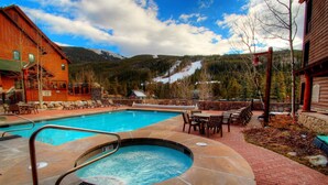 A pool area with a hot tub, outdoor seating, and a mountainous backdrop. - 47 River Run Townhomes 3 Bedroom Townhouse by RedAwning (Keystone)