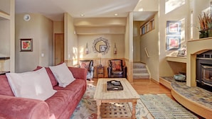 A spacious living room with a red sofa, wooden coffee table, and a fireplace. - 1926 Soda Springs Ii 3 Bedroom Townhouse by RedAwning (Keystone)