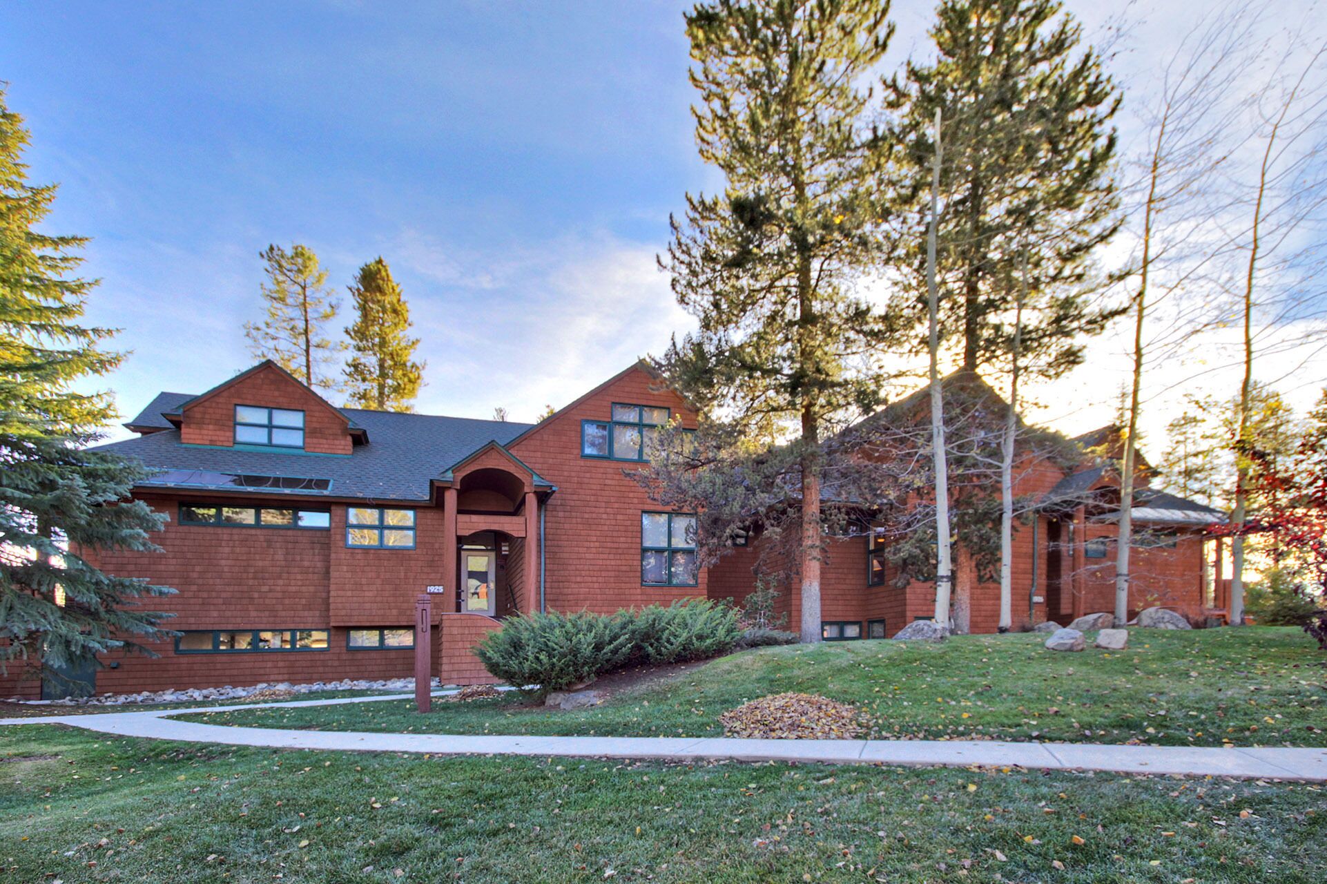 A two-story brick house with a prominent front entrance, large windows, and a well-maintained lawn.