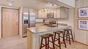 Una cocina moderna con electrodomésticos de acero inoxidable, armarios de madera y una zona de bar con taburetes.
