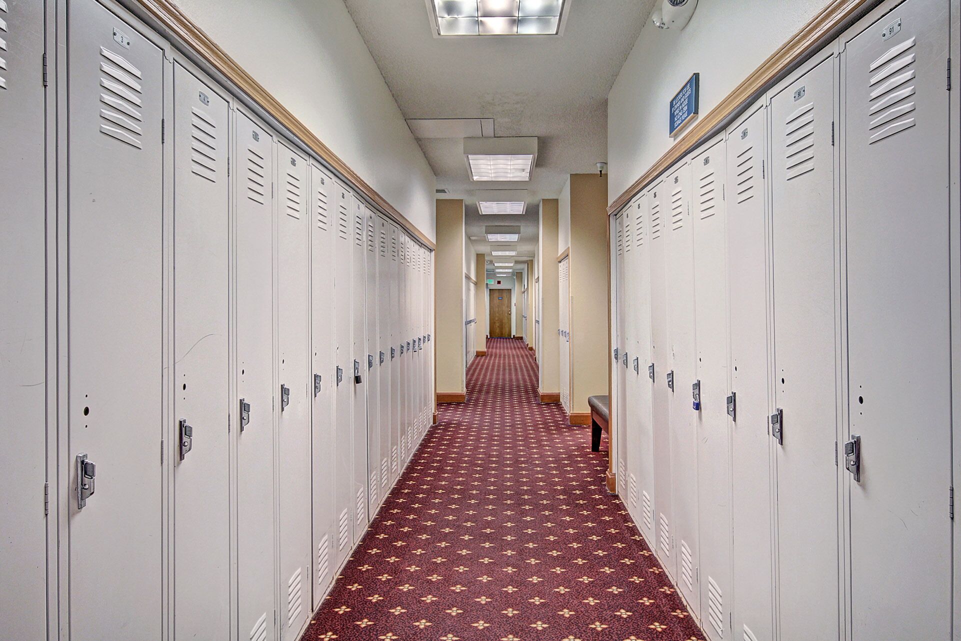 A long hallway with lockers on both sides and a patterned carpet.
