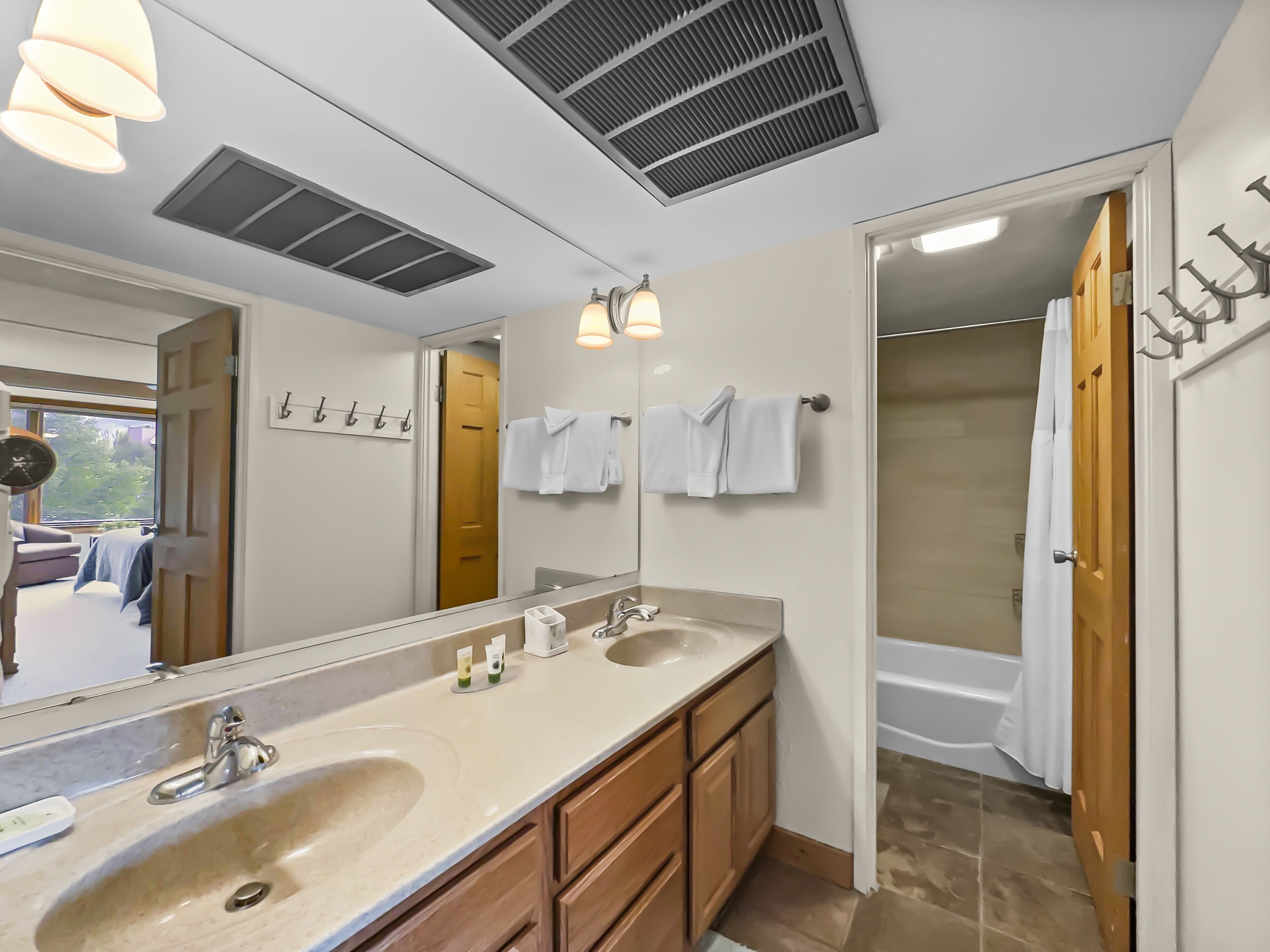 A modern bathroom with a large mirror, two sinks, and a shower area.