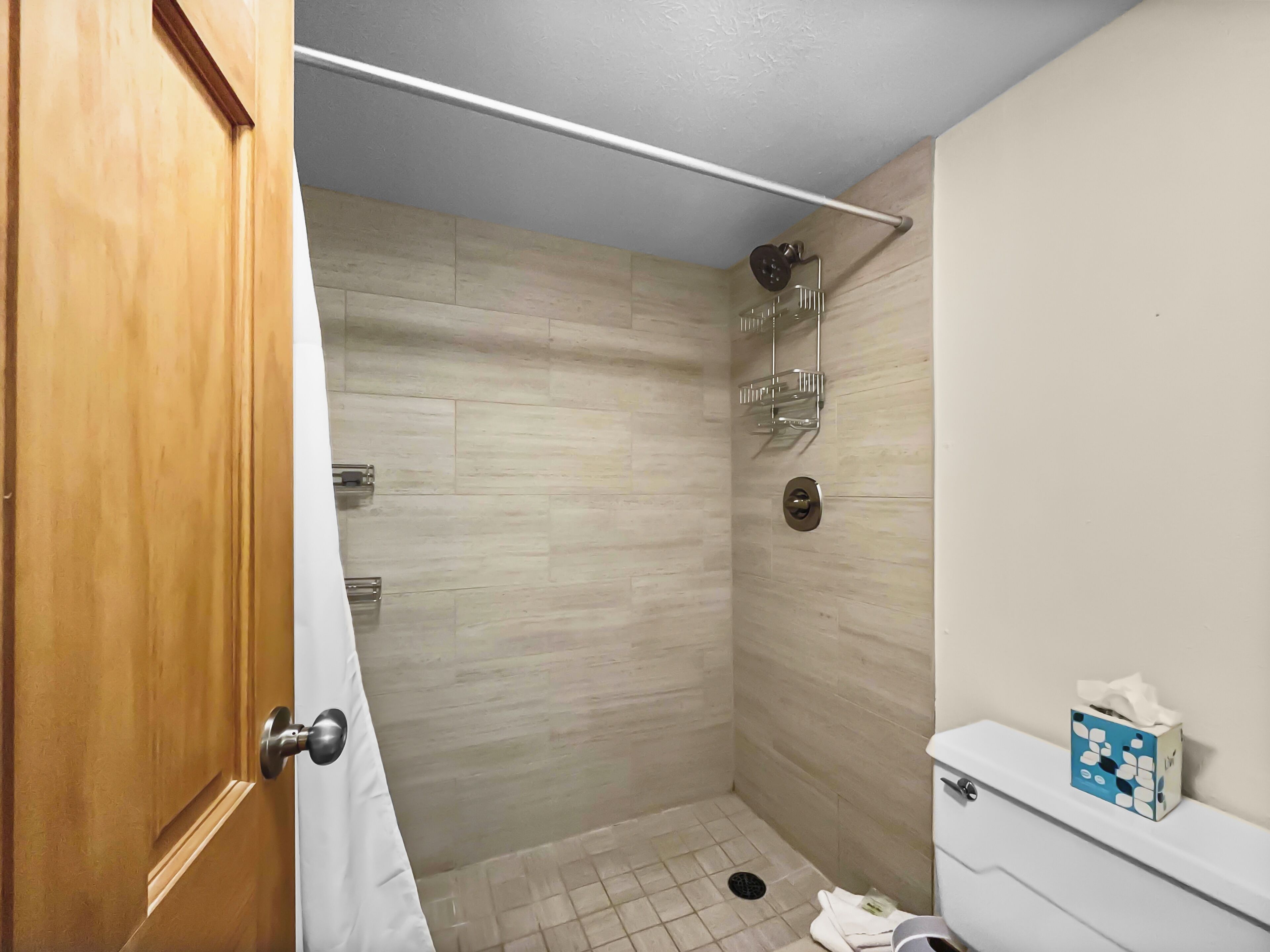 Ein kleines, modernes Badezimmer mit Dusche, Toilette und Handtuchhalter.