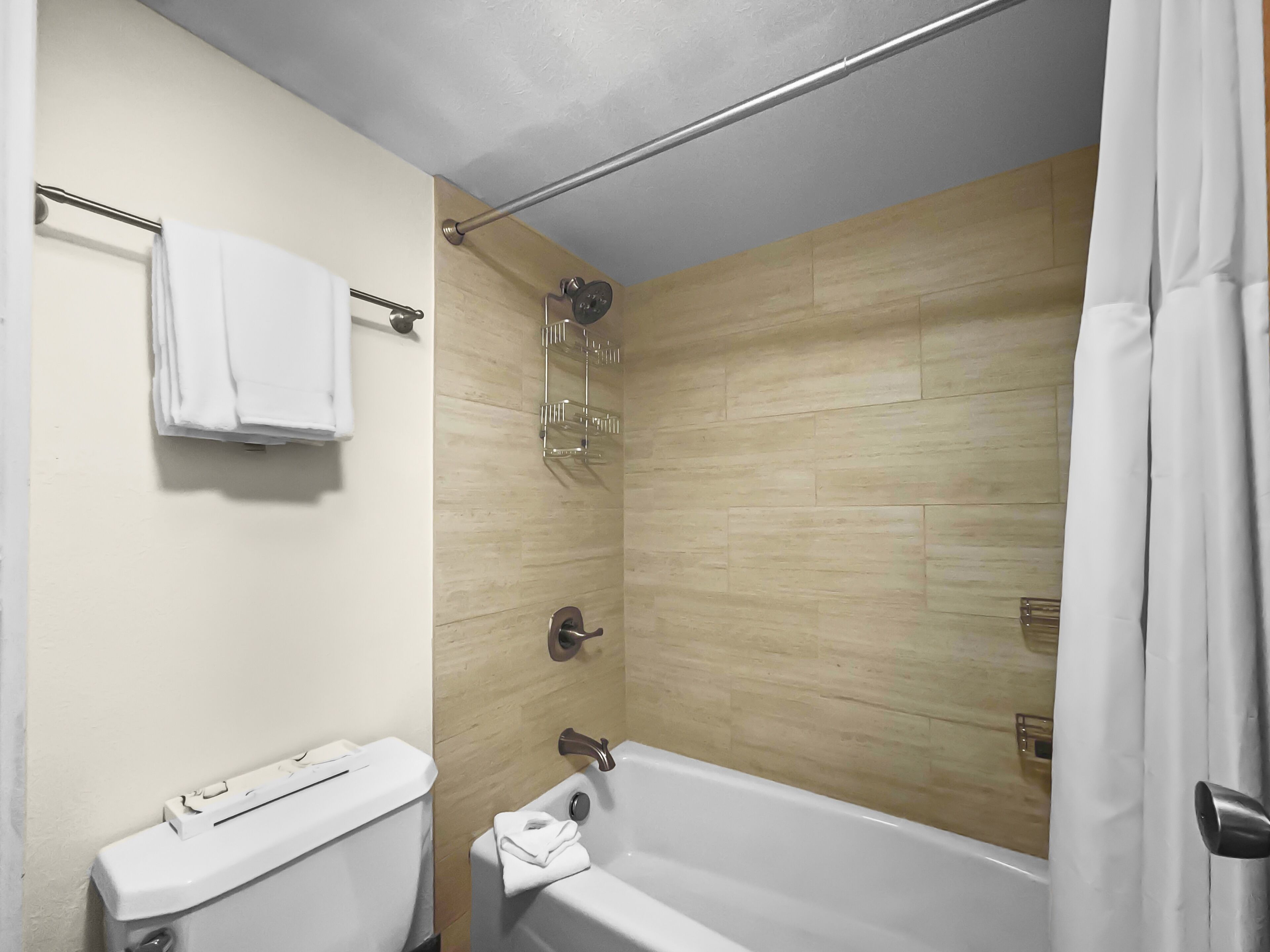 A bathroom with a toilet, a bathtub, and a shower area.