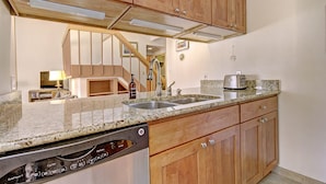 A kitchen with wooden cabinets, a granite countertop, a dishwasher, and a toaster.