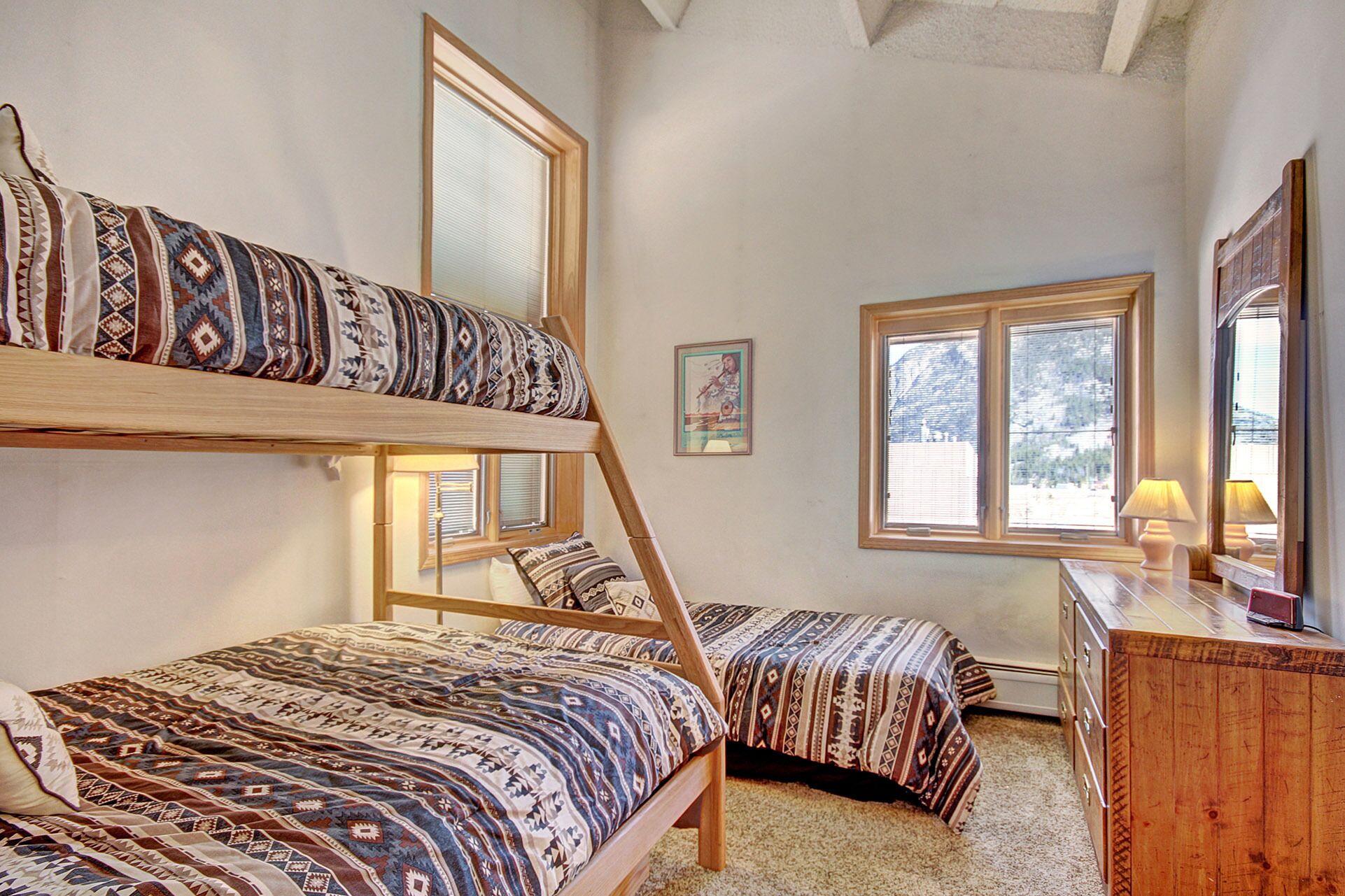 A room with bunk beds, a desk, and a window.